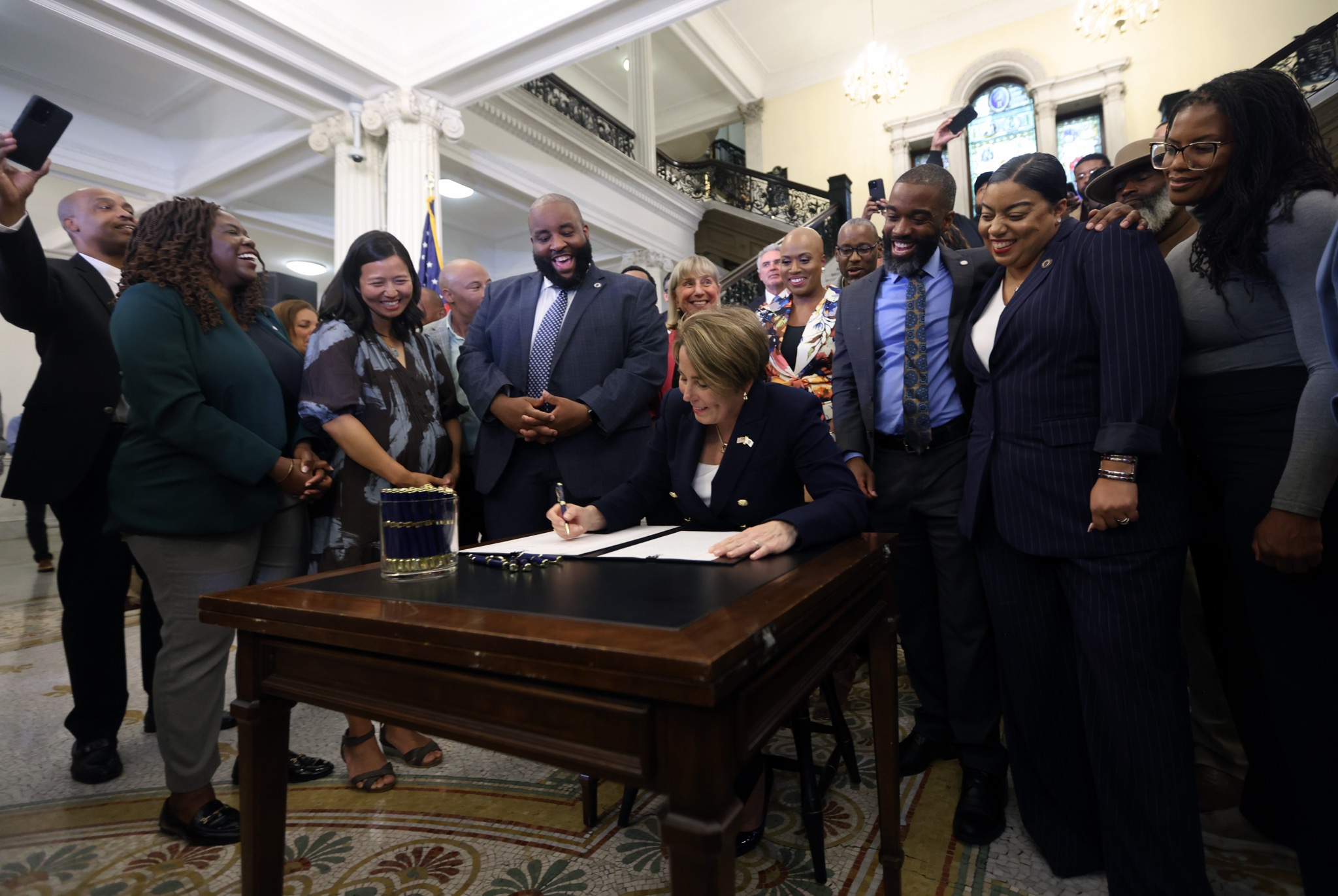 Governor Healey signing the liquor license reform bill with Chris Worrell and supporters